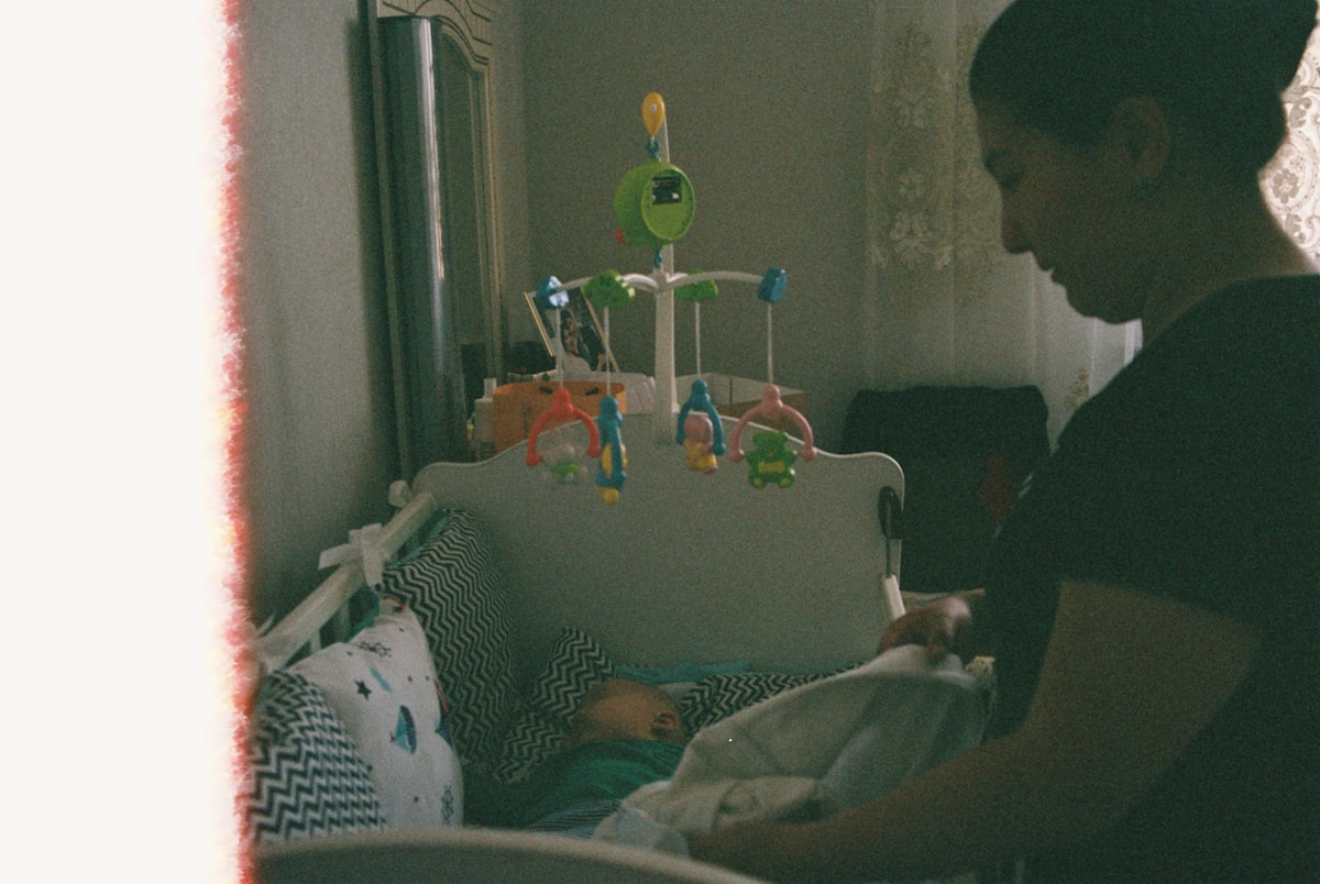 Mother tucking in her baby in a crib related to Nursery Valance Curtains: Add a Touch of Elegance to the Nursery