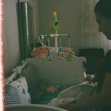 Mother tucking in her baby in a crib related to Nursery Valance Curtains: Add a Touch of Elegance to the Nursery