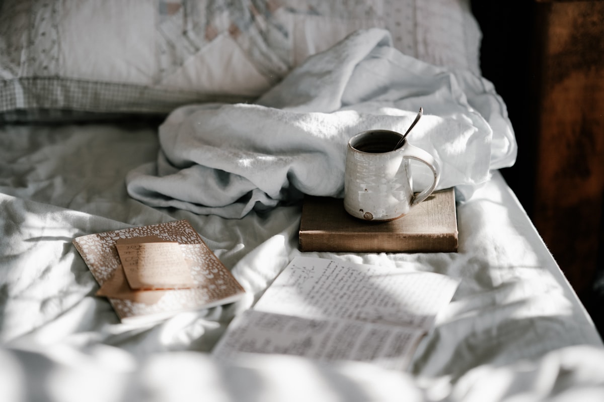 Mug and notebooks on bed related to Bed Bath & Beyond Hours: Your Guide to Shopping Convenience