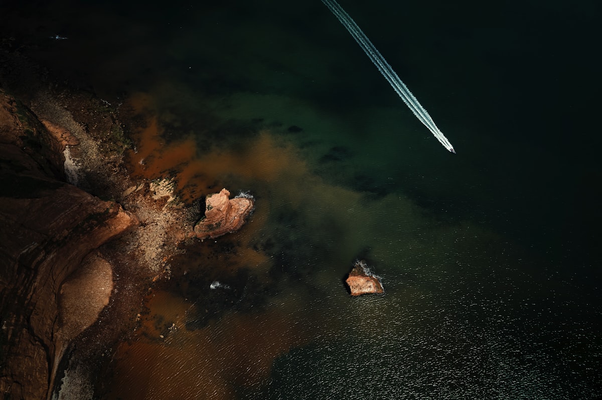 Near Earth Object. A power boat rocketing past the rock stacks along the Jurassic Coast, Sidmouth, Devon, UK related to Capturing the Coastline: A Deep Dive into Coastal Quilts and Coverlets