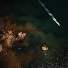 Near Earth Object. A power boat rocketing past the rock stacks along the Jurassic Coast, Sidmouth, Devon, UK related to Capturing the Coastline: A Deep Dive into Coastal Quilts and Coverlets