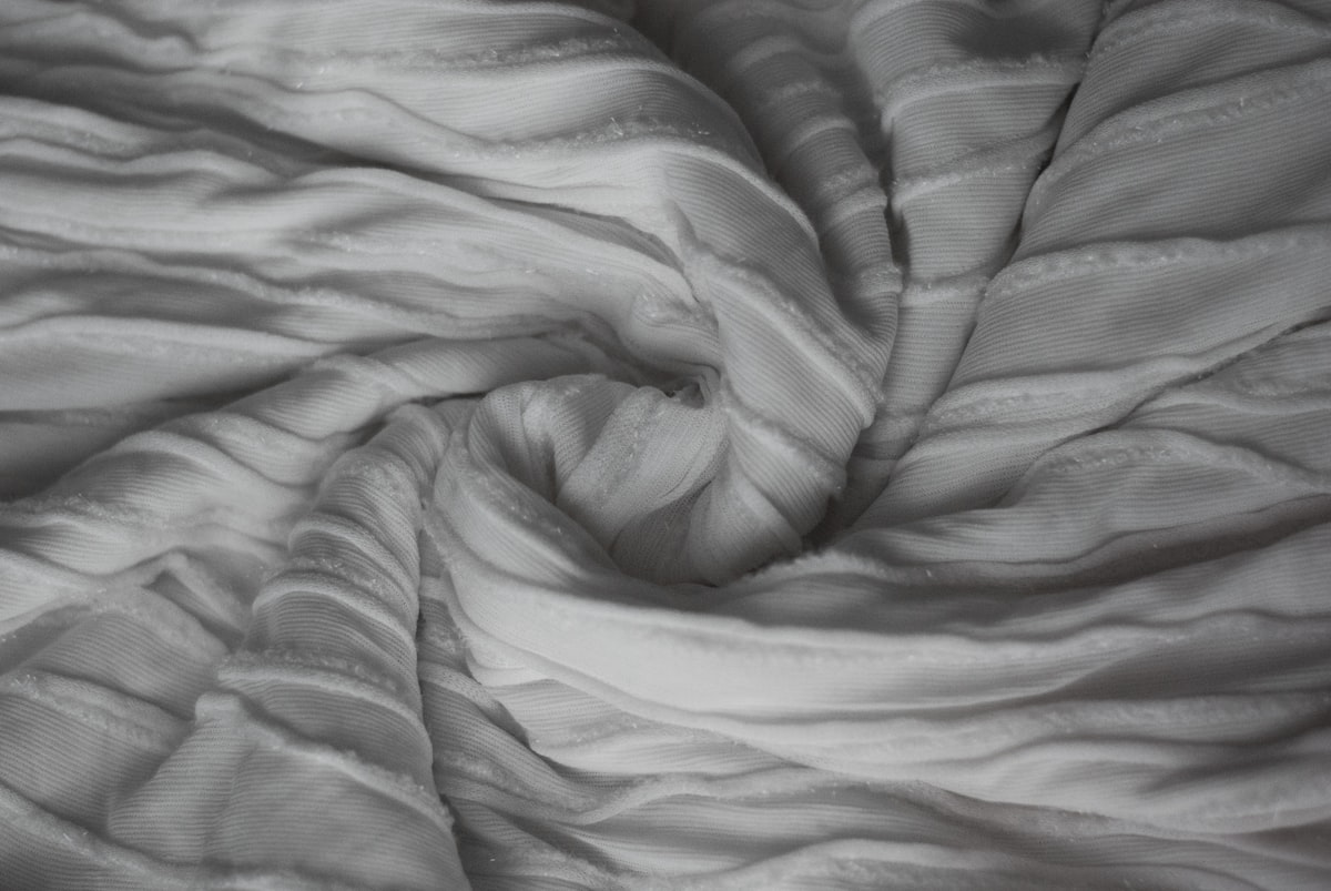 Neatly curled fabric folds in a circle related to White Quilted Coverlet King