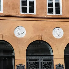 Orange building facade with arched windows and circular reliefs. related to Welcoming Style: Decorating an Entryway