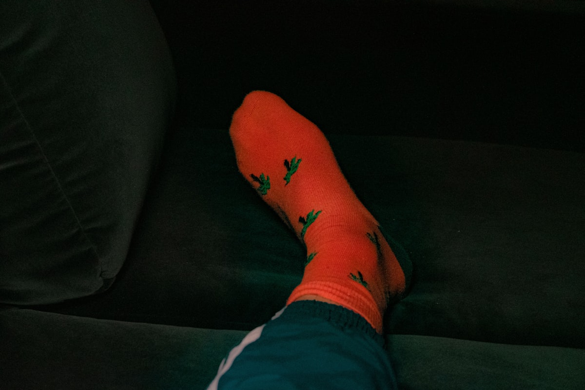orange socks with palm trees on a green velvet couch related to Relieving Nocturnal Leg Discomfort: Why Legs Ache at Night in Bed