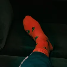 orange socks with palm trees on a green velvet couch related to Relieving Nocturnal Leg Discomfort: Why Legs Ache at Night in Bed