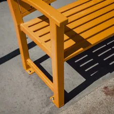 Orange wooden bench casting a shadow on pavement related to Crafting the Perfect Entryway Bench: A Comprehensive Guide to Woodworking Plans