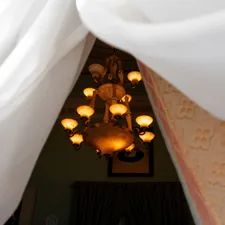 Ornate chandelier illuminated through white curtains related to Elevate Your Sleep Experience with Canopies for Beds