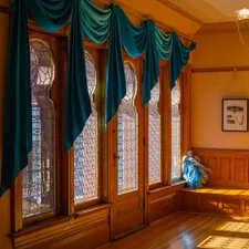 Ornate windows with teal drapes and wooden bench related to Swag Valance Curtains