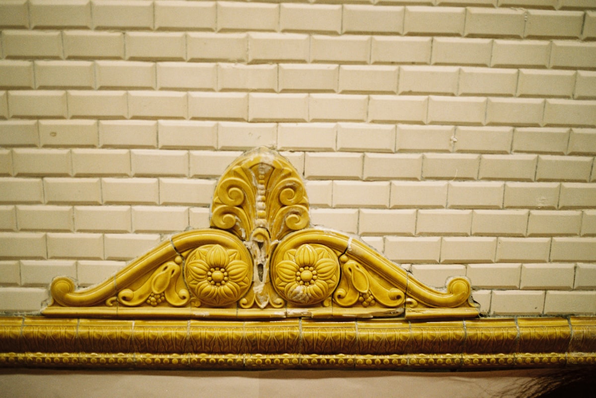 Ornate yellow architectural detail on tiled wall related to The Timeless Beauty of Antique Brass Beds