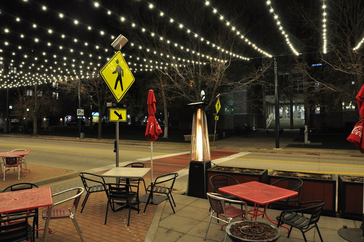Outdoor cafe seating with string lights at night related to Choosing the Perfect Patio Heater: Cast Iron or Clay Chiminea?
