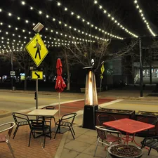 Outdoor cafe seating with string lights at night related to Choosing the Perfect Patio Heater: Cast Iron or Clay Chiminea?