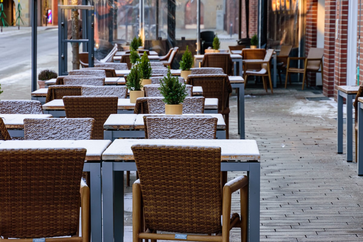 Outdoor cafe tables and chairs covered in light snow. related to Warm Up Your Outdoor Space with Style: Cast Aluminum Chiminea