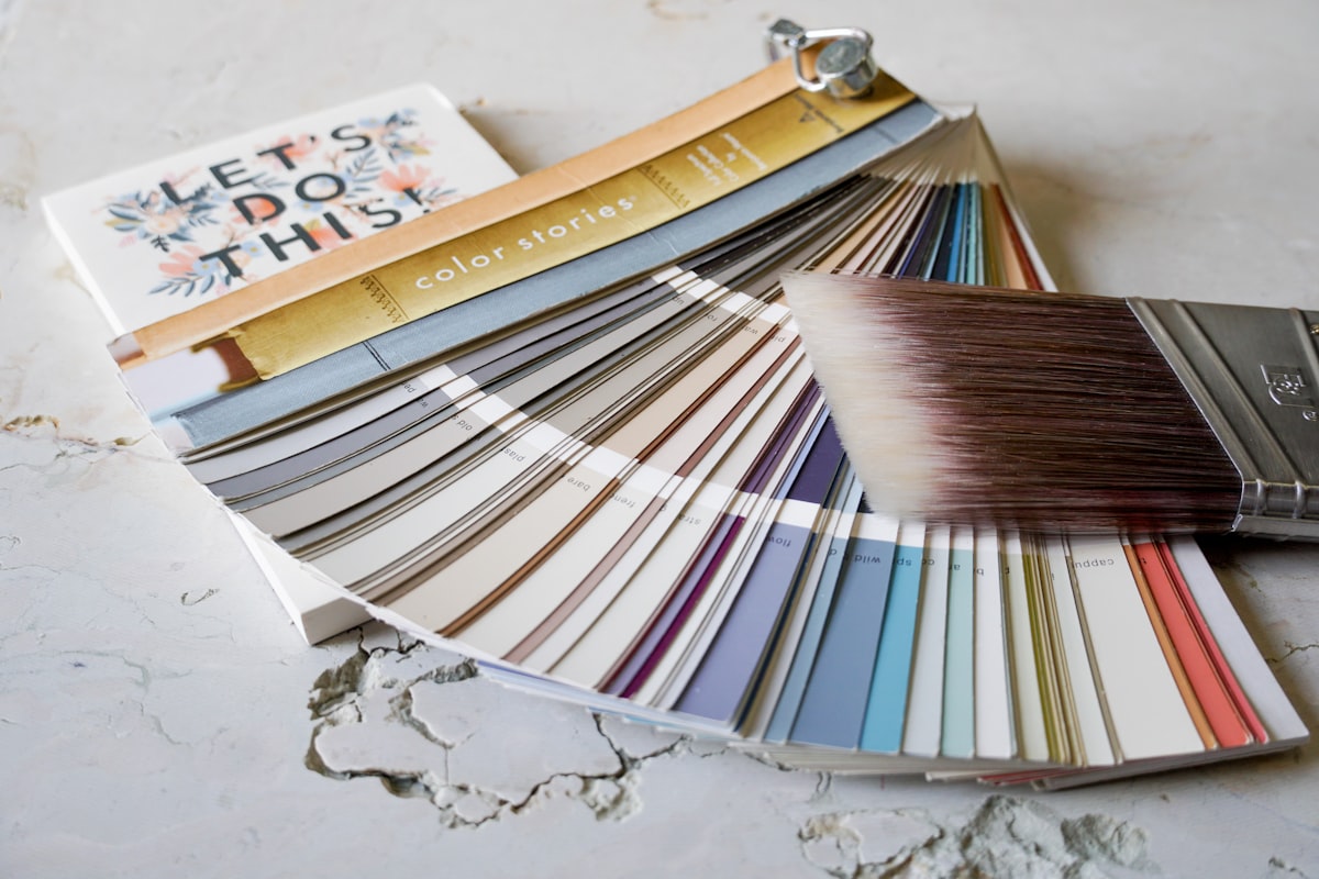 Paint brush and paint colors on table top with notepad related to Welcoming Hues: The Ultimate Guide to Entryway Paint Colors