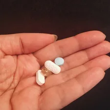 person holding four assorted medicine tablets related to Prolong Your Passion: Boosting Sexual Performance Naturally