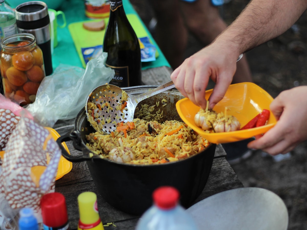 person holding yellow plastic bowl with food related to Cooking on Chiminea: A Delicious Outdoor Experience