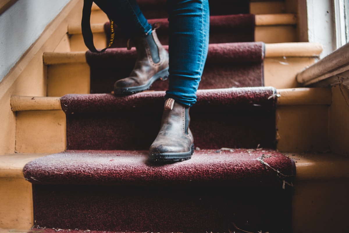 person in blue denim jeans and black leather boots sitting on red staircase related to Enhancing Comfort and Safety at Home