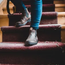 person in blue denim jeans and black leather boots sitting on red staircase related to Enhancing Comfort and Safety at Home