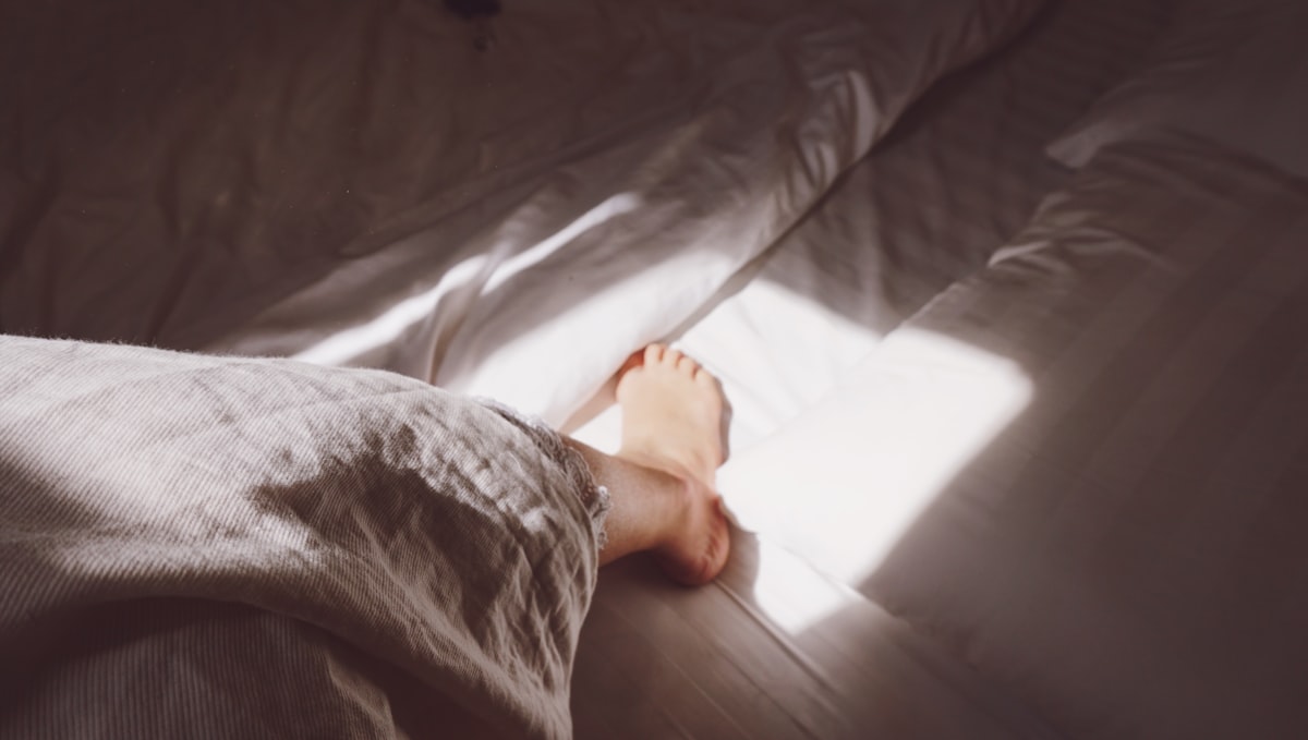 person in grey and black pants lying on bed related to Enhancing the Comfort and Style of Your Bedroom with Foot-of-Bed Solutions