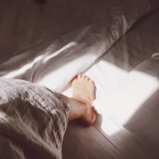 person in grey and black pants lying on bed related to Enhancing the Comfort and Style of Your Bedroom with Foot-of-Bed Solutions