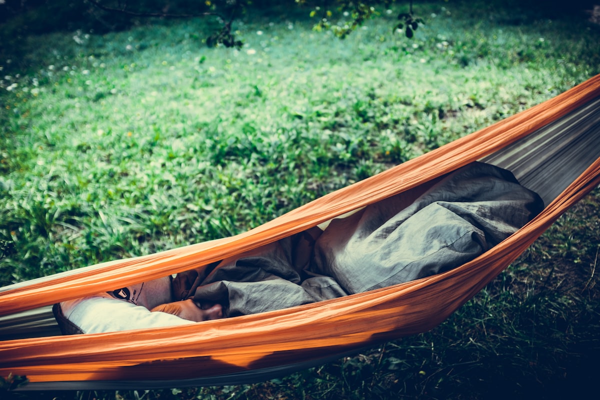 person lying on orange hammock outdoors related to The Ultimate Guide to Choosing the Perfect Camping Bed Roll