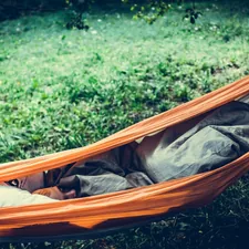 person lying on orange hammock outdoors related to The Ultimate Guide to Choosing the Perfect Camping Bed Roll