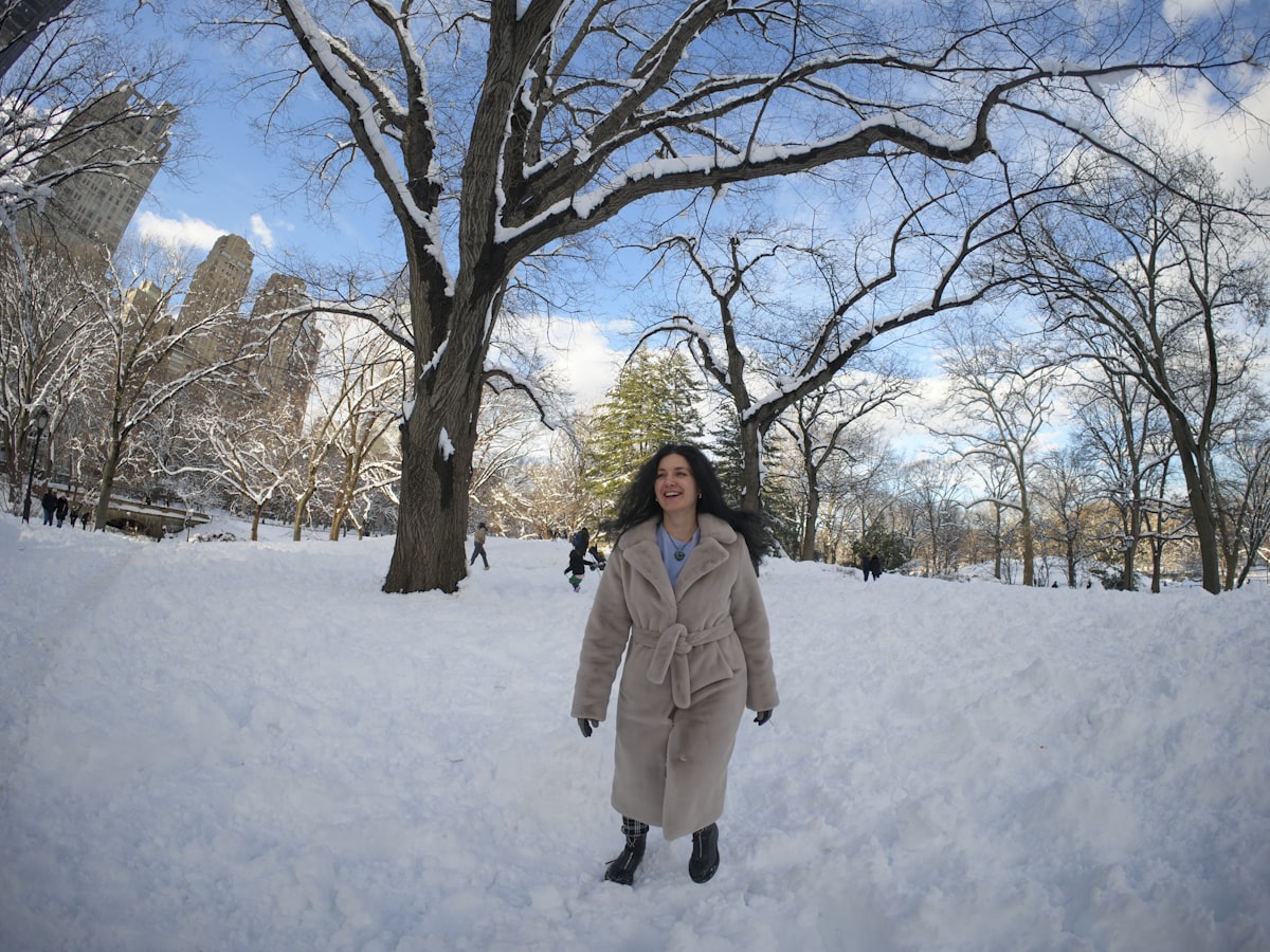 Photo by Olek Buzunov @buzunov.photoart. She is a Ukrainian singer living in NYC, captured during a personal winter photoshoot in Central Park. Surrounded by fresh snow and soft natural light, she interacts playfully with a snowman and poses among bare trees and city skyline views. The neutral tones of her coat contrast beautifully with the crisp white landscape, creating a calm, cozy atmosphere that blends urban life with seasonal serenity. related to Explore the Comfort and Style of Rooms to Go Full Size Beds
