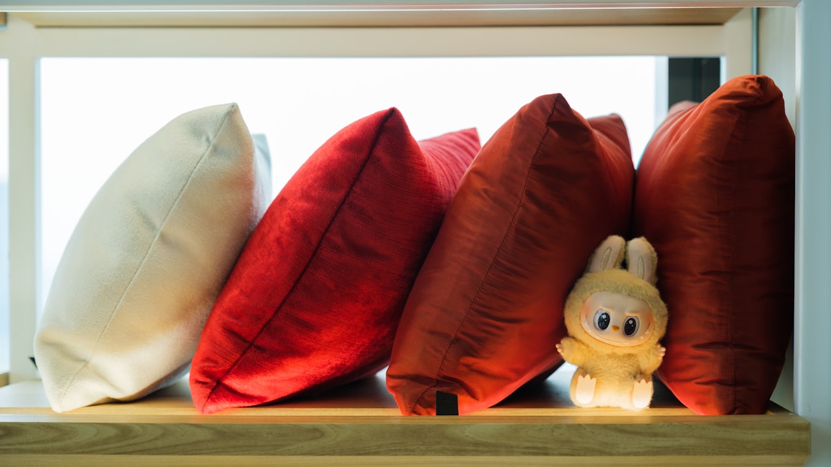 Pillows and a stuffed animal rest on a shelf. related to The Ultimate Guide to Bed Bath and Beyond Cushions: Comfort and Style Combined