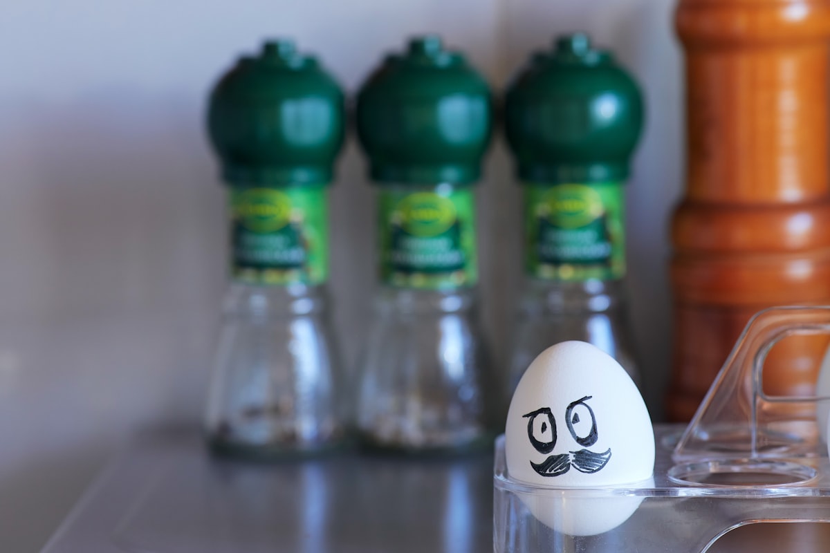 President Lukashenko's evil face painted on a white egg. Painted face on a pure white egg in a stand, lying in the kitchen against the background of spices and blurred wall. Political caricature in the kitchen related to Cozy Up with the Green Egg Chiminea