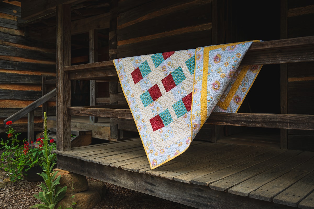 Quilt draped over a wooden porch railing related to Coverlets and Quilts Contemporary