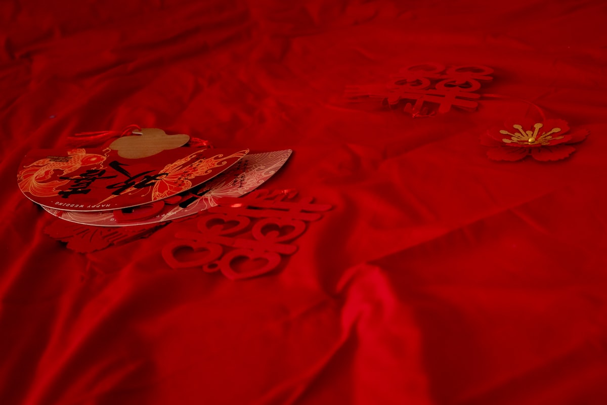 Red background with paper decorations and a small golden object. related to Transform Your Bedroom with Elegant Red Bedding Options
