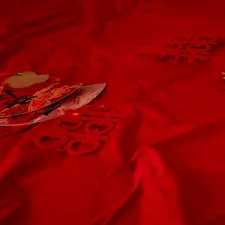 Red background with paper decorations and a small golden object. related to Transform Your Bedroom with Elegant Red Bedding Options