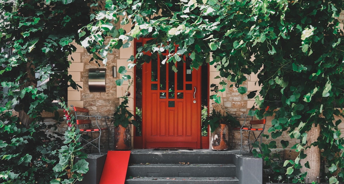 Red door from an overgrown house related to Elevate Your Entrance: Decorating with Entryway Tables and Mirrors