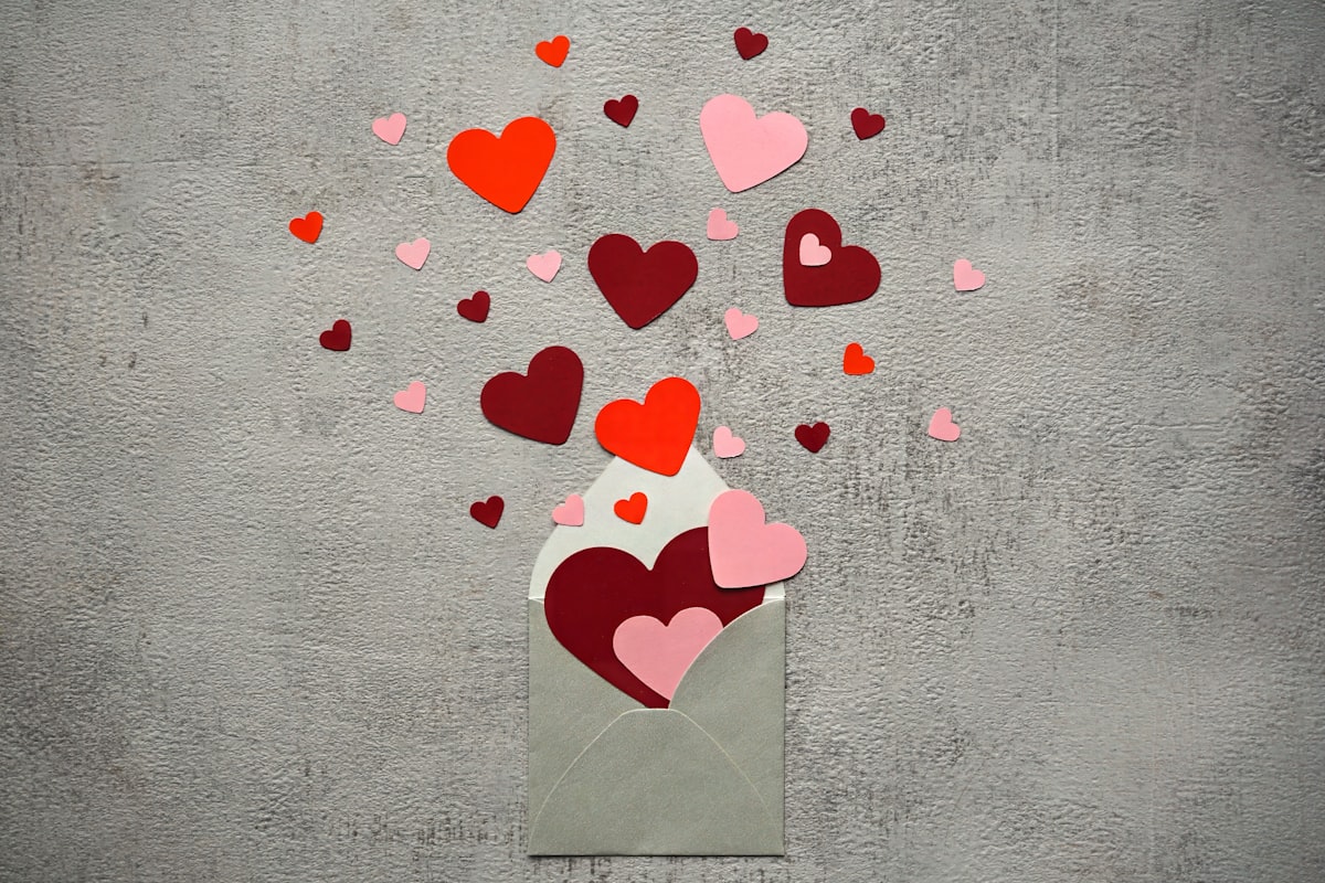 Rote und rosa Herzen fliegen aus einem Briefumschlag, Hintergrund grau. related to Dr. Seuss Valentine's Day