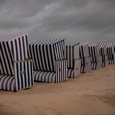 Row of striped beach chairs on a sandy beach related to The Ultimate Beach Bed Set: Comfort and Style by the Shore
