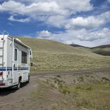 Rv parked on a dirt road with rolling hills. related to Choosing the Best Ladder for Your RV Bunk Bed