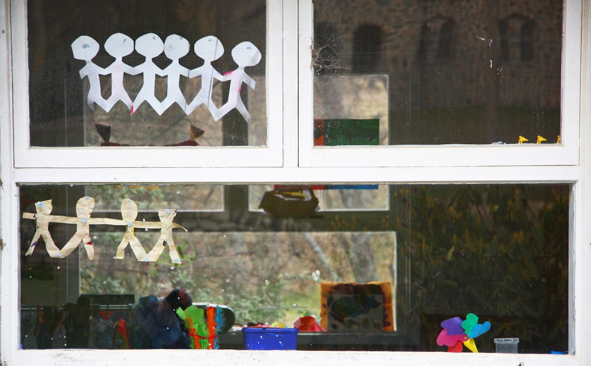 School window with paper cutouts and bright objects in the background. related to Elevate Your Window Game: A Guide to Simple Window Valances