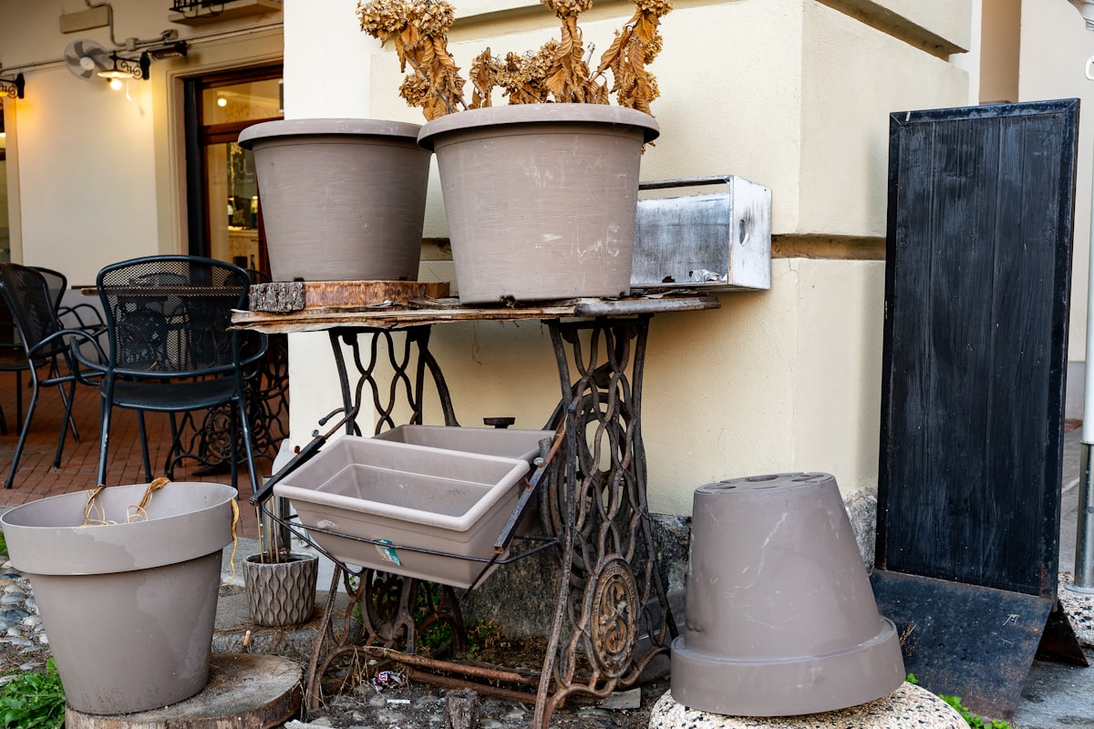 Several empty planters on an antique sewing machine base. related to Embracing the Heat: Large Cast Iron Chimineas for Your Outdoor Space