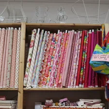 Shelves are filled with colorful fabric bolts. related to Pink Quilts and Coverlets