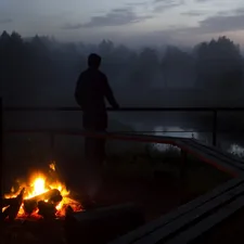 silhouette photo of a person standing near body of water and bonfire related to Cozying Up with an Outdoor Fire Chiminea