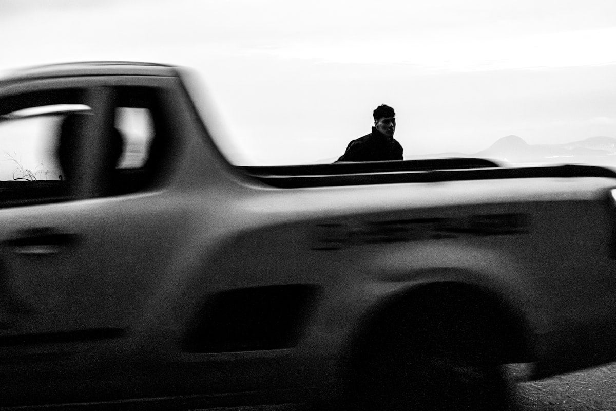 Silhouetted figure in blurred moving truck, a stark, grainy, fleeting journey. related to Protecting and Personalizing Your Truck with the Best Truck Bed Caps