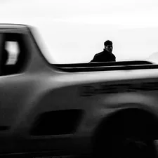 Silhouetted figure in blurred moving truck, a stark, grainy, fleeting journey. related to Protecting and Personalizing Your Truck with the Best Truck Bed Caps