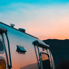 Silver travel trailer against a sunset sky. related to Cozy Up on the Open Road: The Ultimate Guide to Travel Trailer Bedding