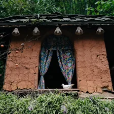 Small rustic building with patterned curtains in window. related to The Rustic Charm of Clay Chimineas: Fueling Gatherings and Memories