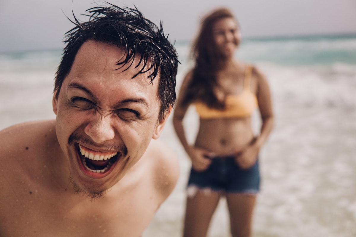 smiling man in blue shorts on beach during daytime related to Why Do Adults Wet the Bed? Uncovering the Causes and Solutions