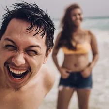 smiling man in blue shorts on beach during daytime related to Why Do Adults Wet the Bed? Uncovering the Causes and Solutions
