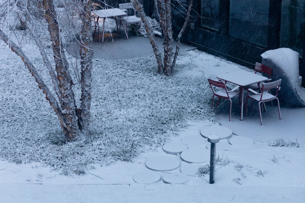 Snow covers an outdoor seating area with tables and chairs. related to Warming Your Outdoor Space with a Delightful Twist: Fish Shaped Chiminea