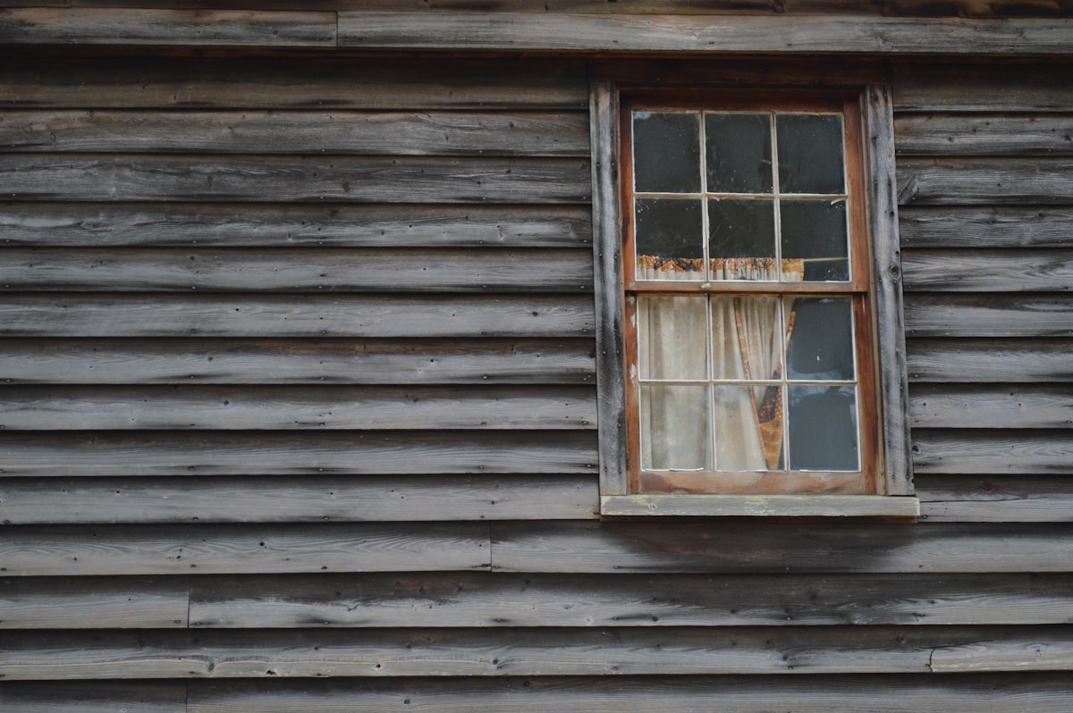Spooky looking haunted window on old cedar wooden house related to Exploring the Charm of Grey Window Valances: A Comprehensive Guide