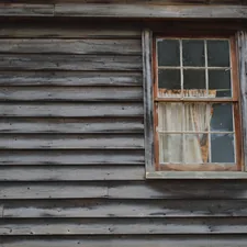 Spooky looking haunted window on old cedar wooden house related to Exploring the Charm of Grey Window Valances: A Comprehensive Guide