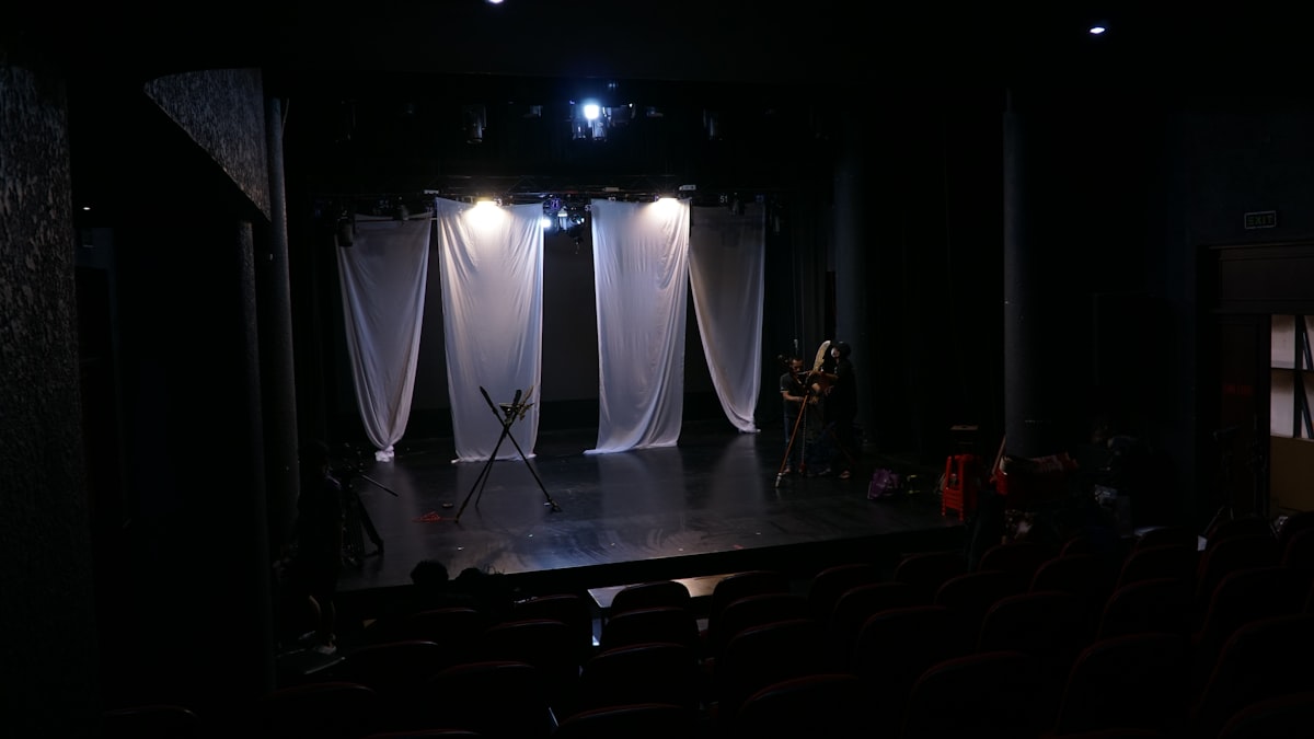 Stage with white curtains and dim lights. related to Dreaming on Stage: The Unique Concept of Theatre with Beds