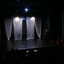 Stage with white curtains and dim lights. related to Dreaming on Stage: The Unique Concept of Theatre with Beds